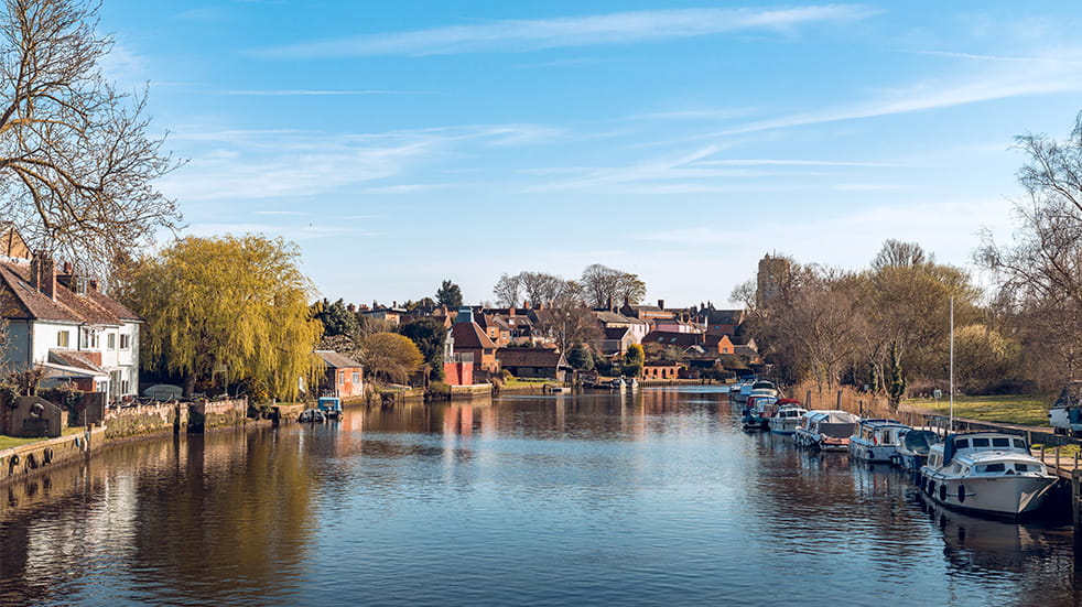 Landscape of a beautiful spot in East Anglia, including riverside houses and boats